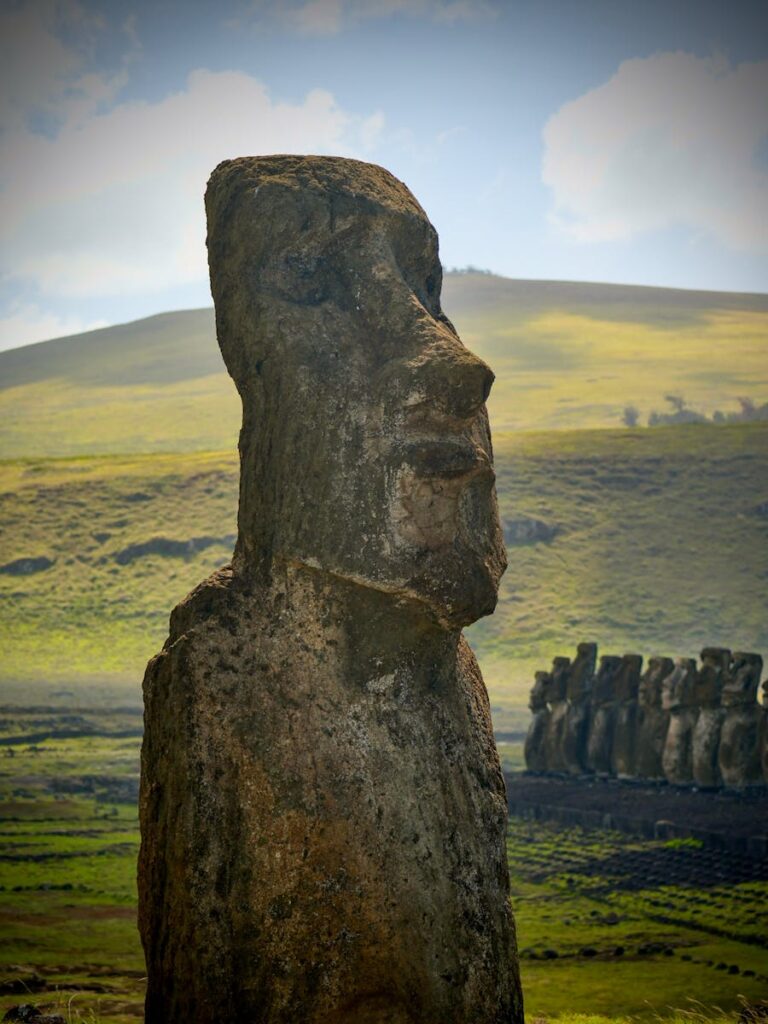 Majestic Moai statue on Easter Island, set against lush green hills.