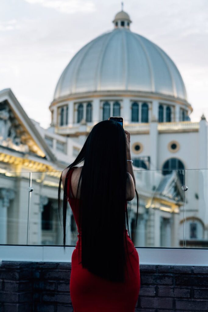 A woman captures a stunning historic dome in El Salvador at sunset, showcasing architectural beauty and cultural heritage.